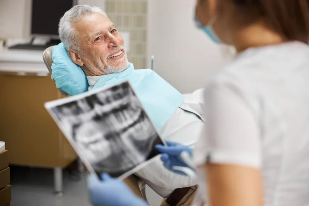 senior citizen listening to a dentist talking about his tooth's x-ray scans
