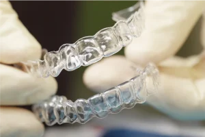 doctors hands holding two Invisalign retainers